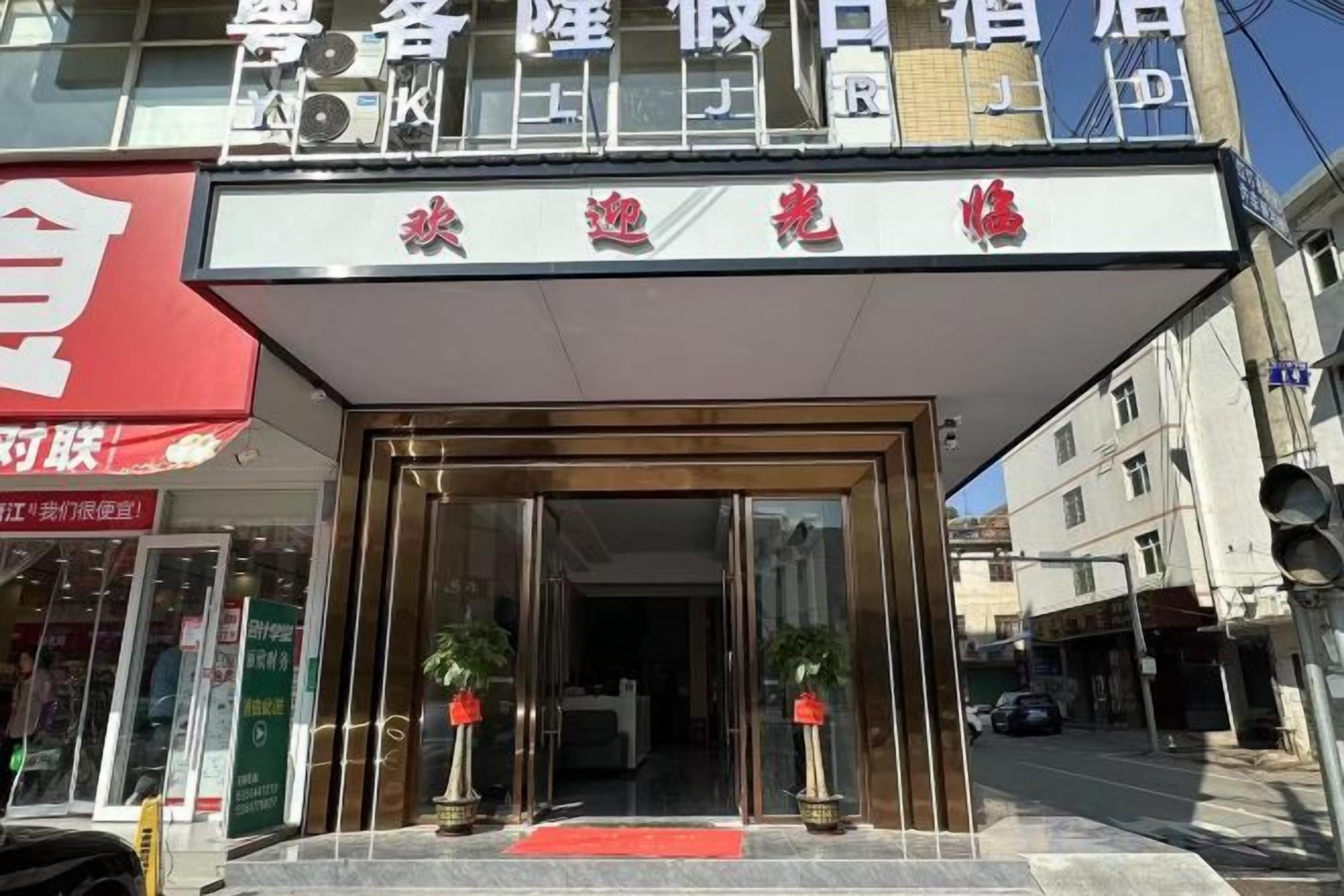 A hotel entrance with a red awning, glass doors, and potted plants.