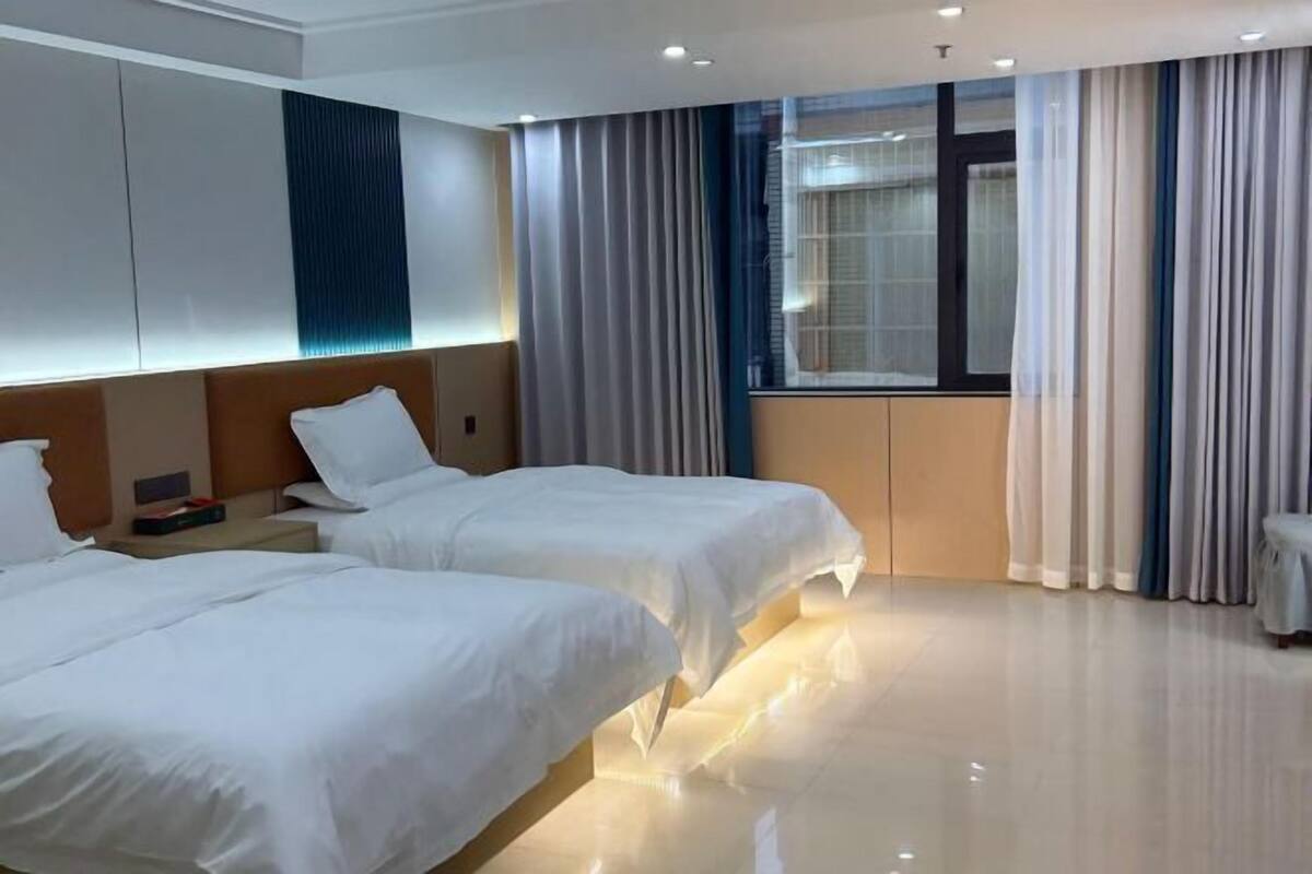 A hotel room with two beds, a nightstand, a window with curtains, and a modern design.