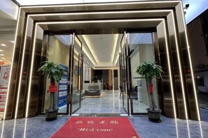 A hotel entrance with a red carpet, glass doors, and potted plants. - Ganzhou Yuekelong Holiday Hotel (Ganzhou)