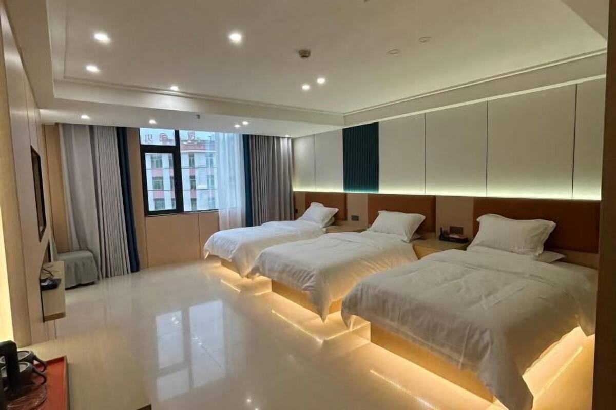 A hotel room with two beds, a large window with curtains, and a modern design.