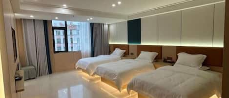 Habitación de hotel con dos camas, un ventanal grande con cortinas y un diseño moderno.