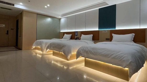 A hotel room with two beds, a large mirror, and a wooden headboard. - Ganzhou Yuekelong Holiday Hotel (Ganzhou)