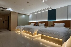 Una habitación de hotel con dos camas, un espejo grande y un cabecero de madera.