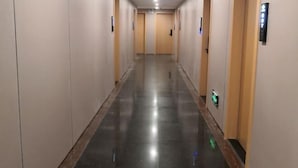 A long, narrow hallway with doors on both sides, a shiny floor, and a light-colored wall. - Ganzhou Yuekelong Holiday Hotel (Ganzhou)