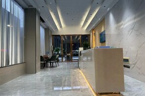 A modern hotel lobby with a reception desk, seating area, and large windows. - Ganzhou Yuekelong Holiday Hotel (Ganzhou)