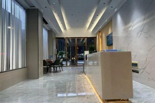 Un moderno vestíbulo de hotel con un mostrador de recepción, zona de estar y grandes ventanales.