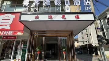 A hotel entrance with a red awning and a signboard above.