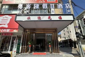 Entrada de hotel con un toldo rojo y un cartel arriba.