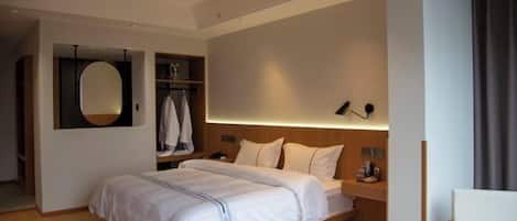 A modern hotel room with a large bed, bedside tables, a mirror, and a seating area.