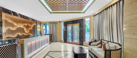 A hotel lobby with a reception desk, seating area, and a geometric floor pattern.