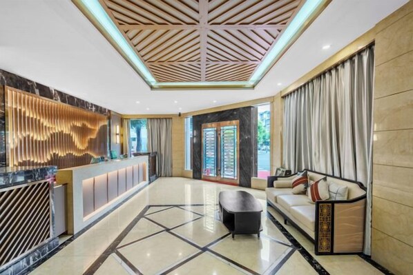 A hotel lobby with a reception desk, seating area, and a geometric floor pattern.