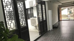 Ein Korridor mit schwarzen Dekortüren, gefliestem Boden und Blick ins Freie.