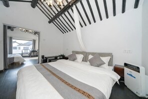 A bedroom with a large bed, a bedside table, a nightstand, and a ceiling fan.