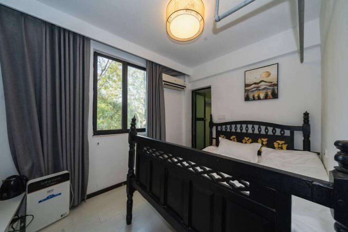 Een slaapkamer met een bed, een raam, een schilderij en een airconditioning.