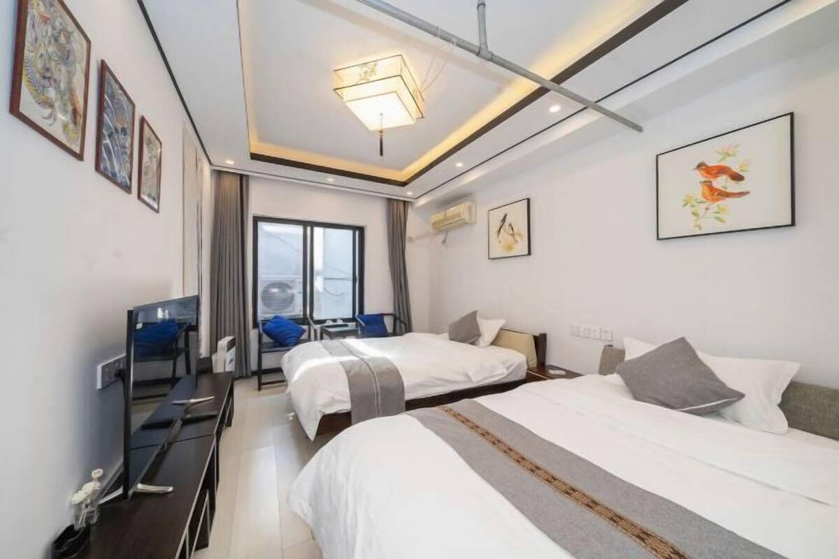 Een hotelkamer met twee bedden, een bureau, een stoel en een groot raam.