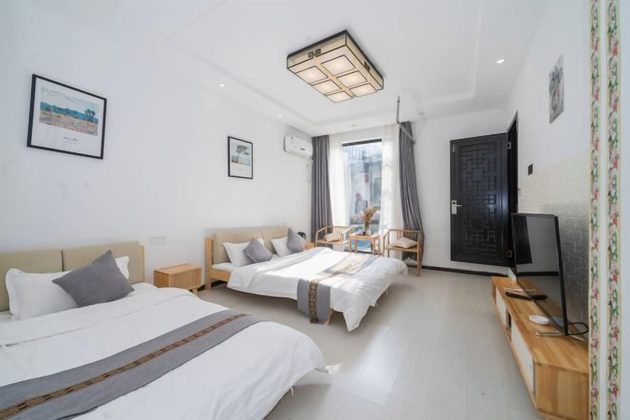 Quarto de hotel com duas camas, televisão, escrivaninha e uma cadeira.