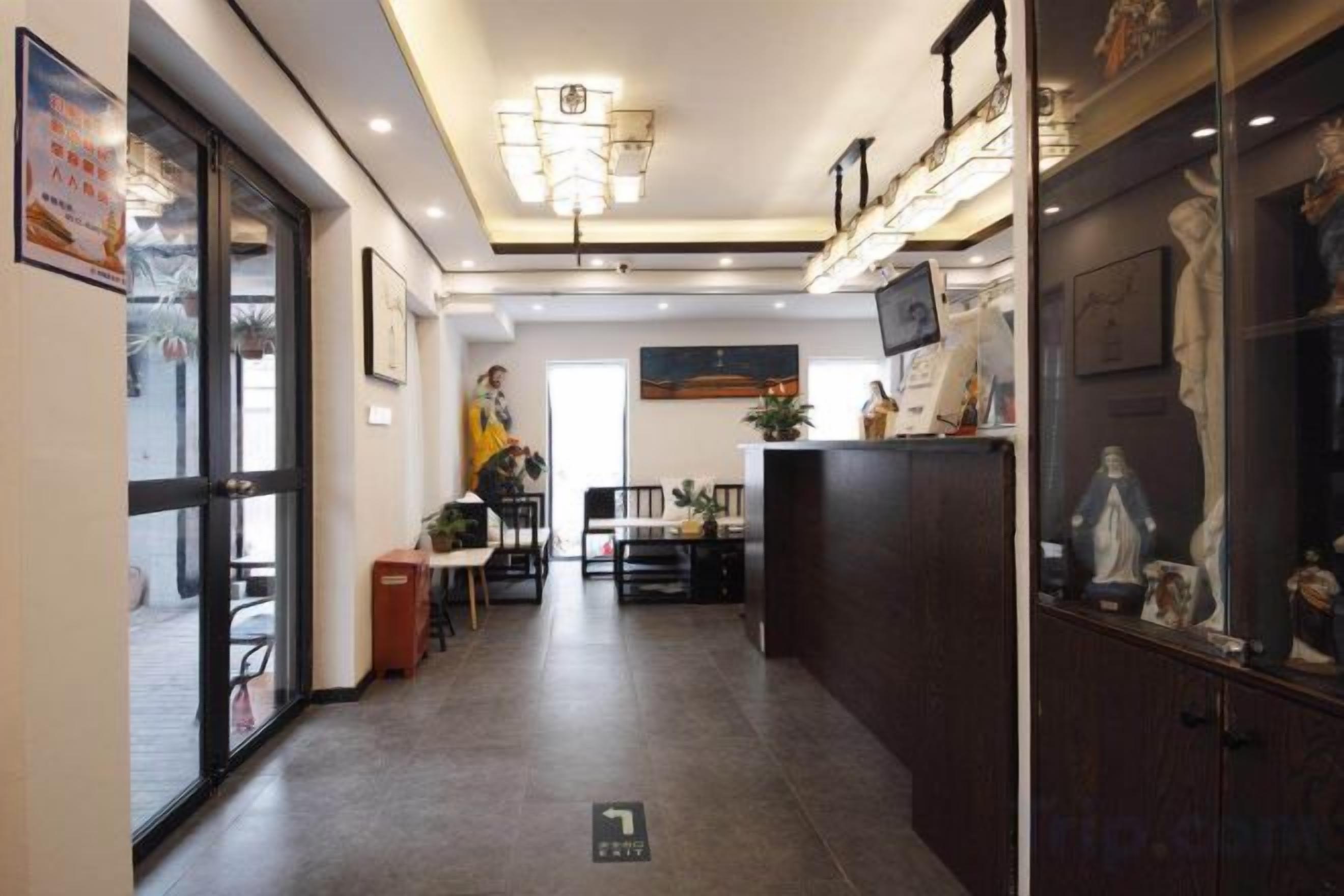 A hotel corridor with a dining area, a reception desk, and a statue display.