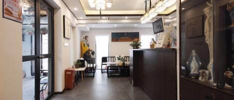 A hotel corridor with a dining area, a reception desk, and a statue display.