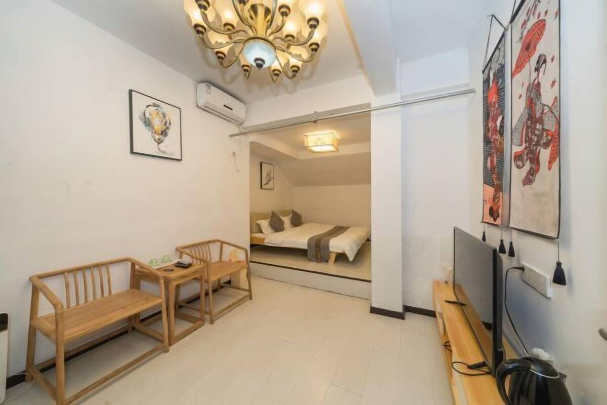 Een kleine kamer met een bed, bureau, stoel en televisie.