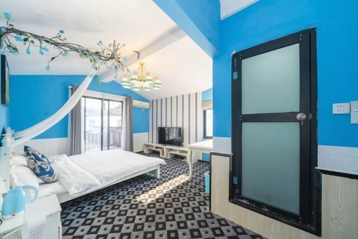 Een hotelkamer met een bed, een bureau, een televisie en een groot raam.