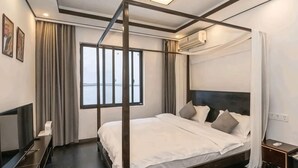 Ein Bett mit Himmelbett, ein dunkles Kopfteil, ein Flachbildfernseher und ein Nachttisch.