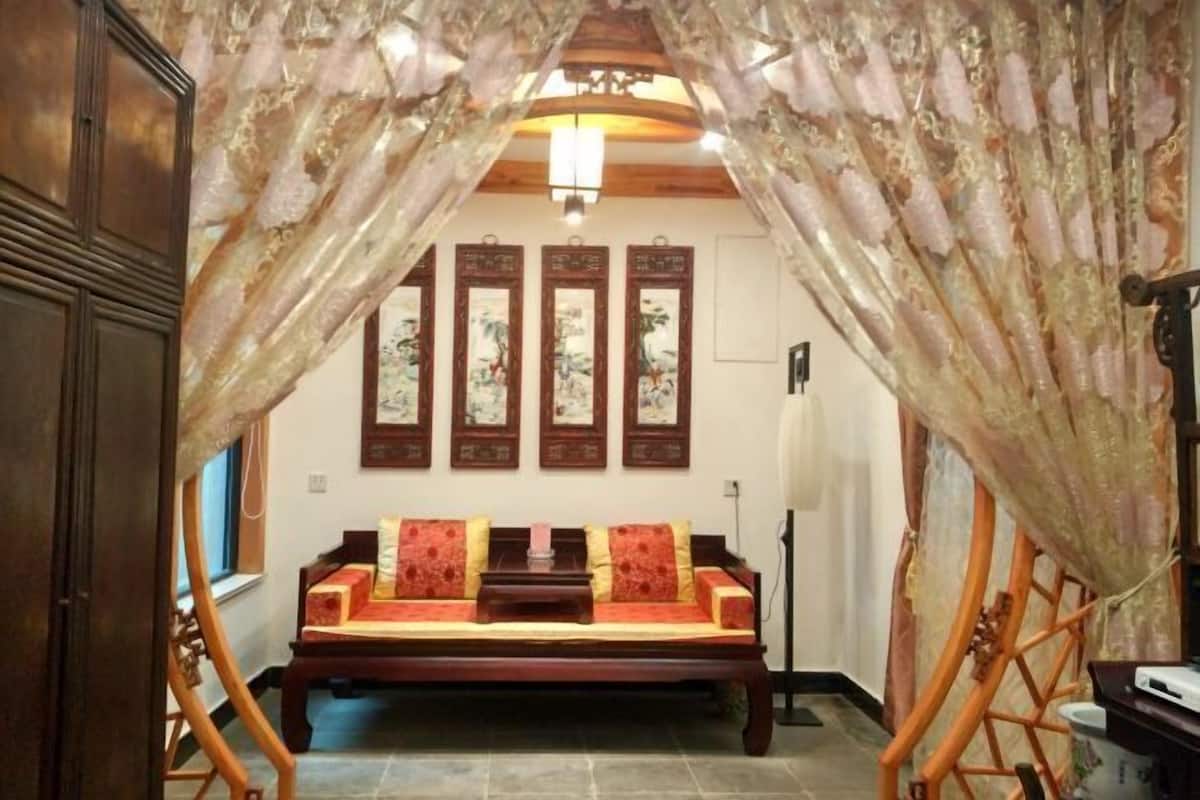 A traditional room with a wooden sofa, a ceiling fan, and a wall with framed artwork.