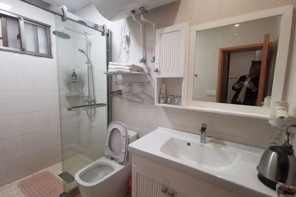 Een badkamer met een douchecabine van glas, een toilet, een wastafel en een spiegel.