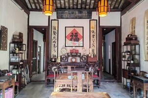 Un interior tradicional con una mesa de madera central y sillas, rodeado de estanterías con diversos objetos.