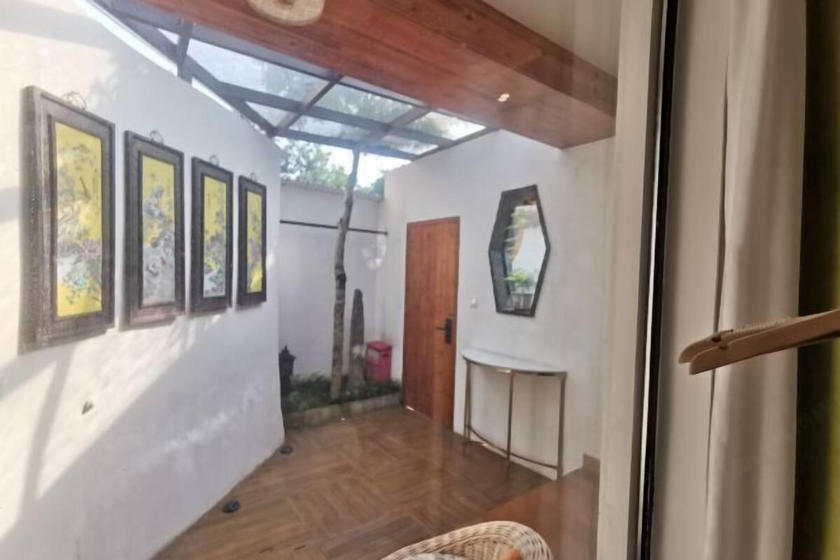 A room with a wooden ceiling, a glass door, a wooden door, and a mirror on the wall.