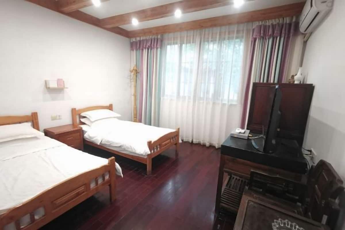 A bedroom with two wooden beds, a television, and a desk.