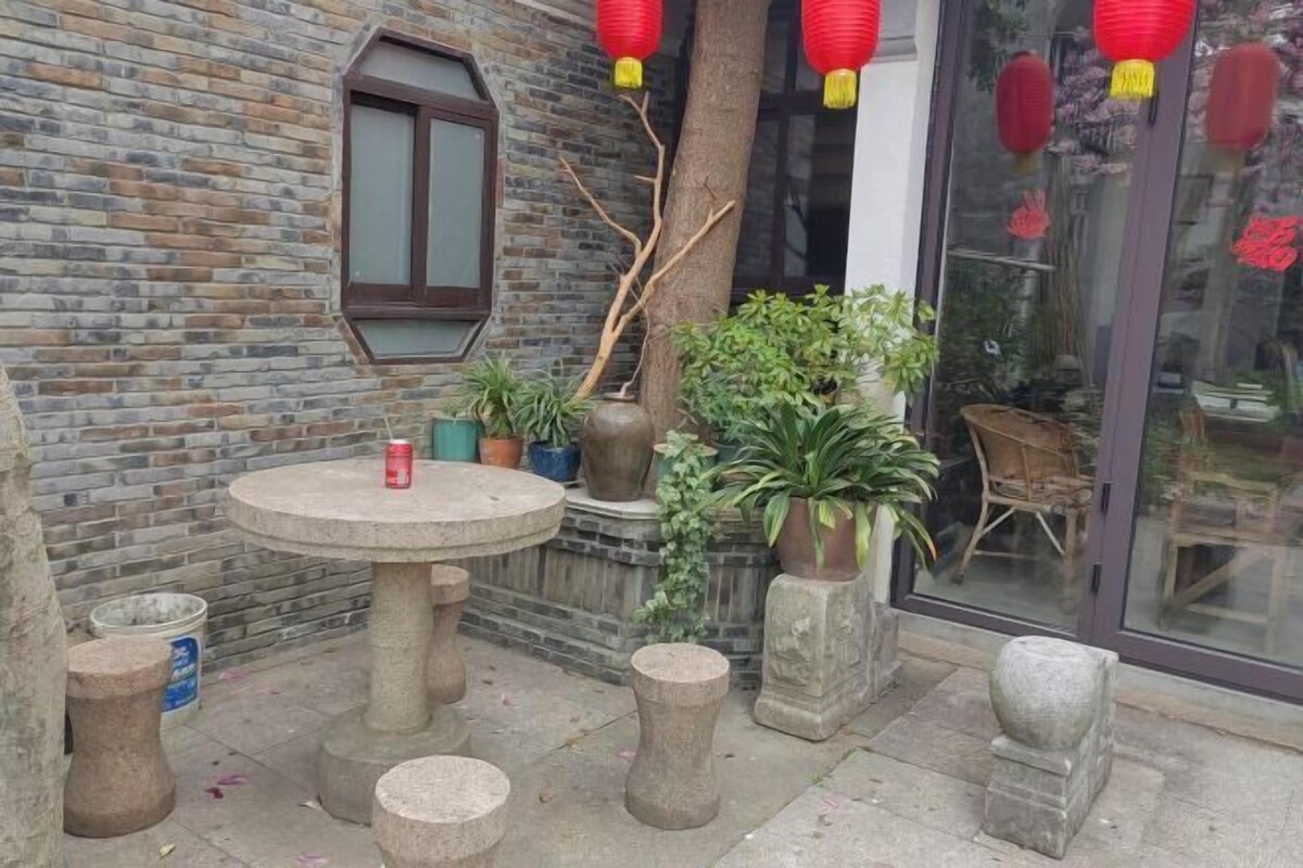 A courtyard with a stone table, potted plants, and a brick wall.