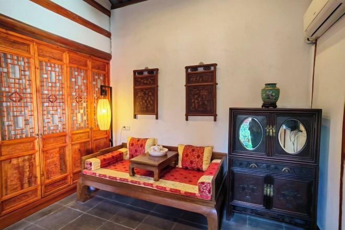 Een klassieke kamer met een houten bank, een kast met spiegels en een decoratief wandpaneel.