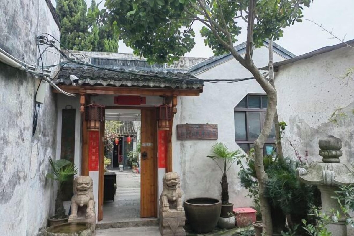 A traditional courtyard with stone lion statues, a tiled roof, and potted plants.