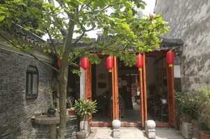 Un patio tradicional con una puerta de madera, plantas en macetas y faroles rojos.