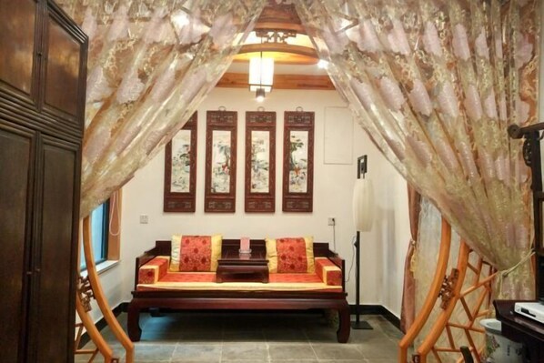 A traditional room with a wooden sofa, a ceiling fan, and a wall-mounted TV.