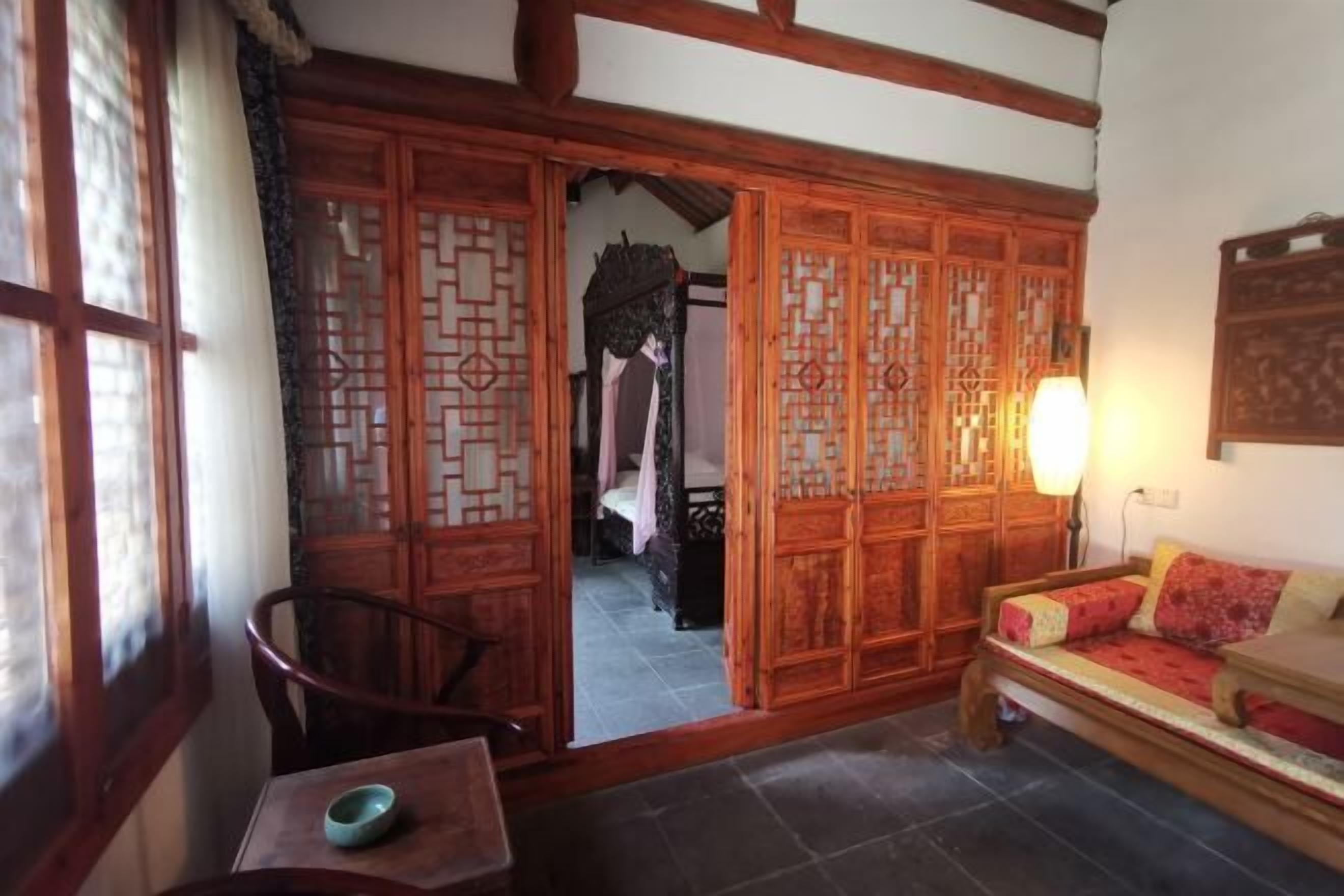Una habitación tradicional con puerta corredera de madera, un sofá, una mesa con un cuenco y una lámpara.