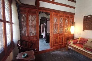 A traditional room with a wooden sliding door, a sofa, a table with a bowl, and a lamp.