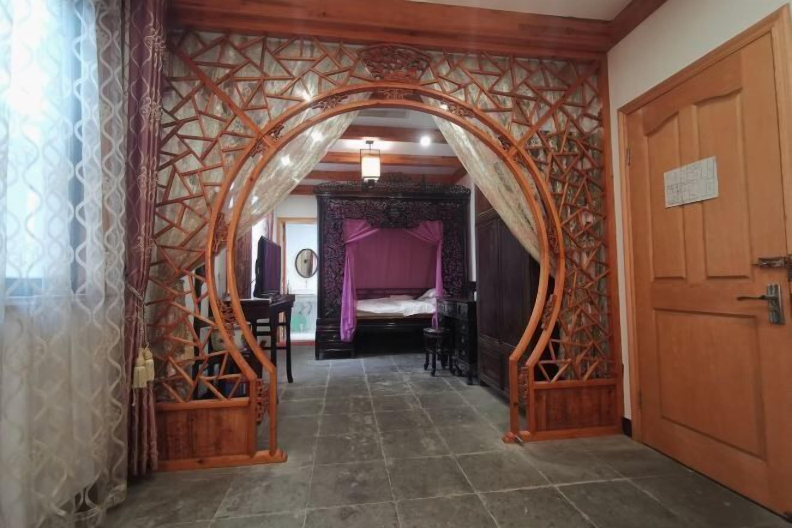 Una habitación con una cama, un arco de madera y una puerta.