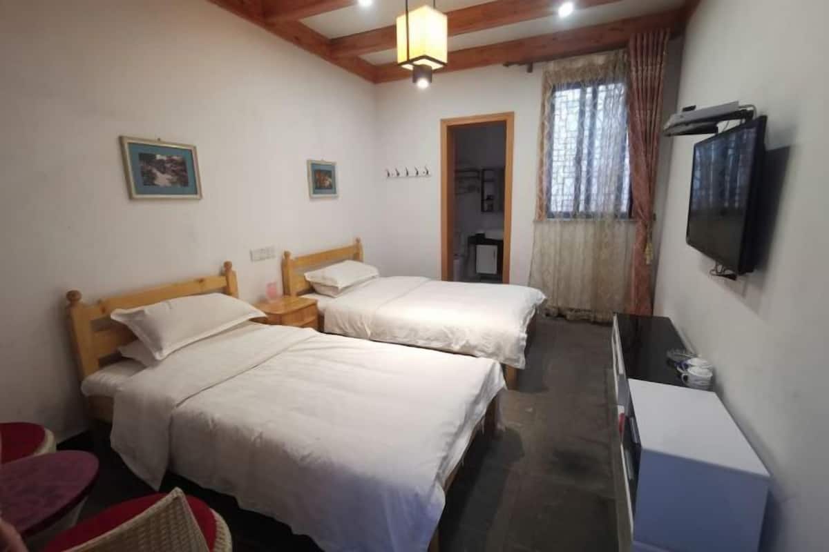 A bedroom with two beds, a TV, and a small table.