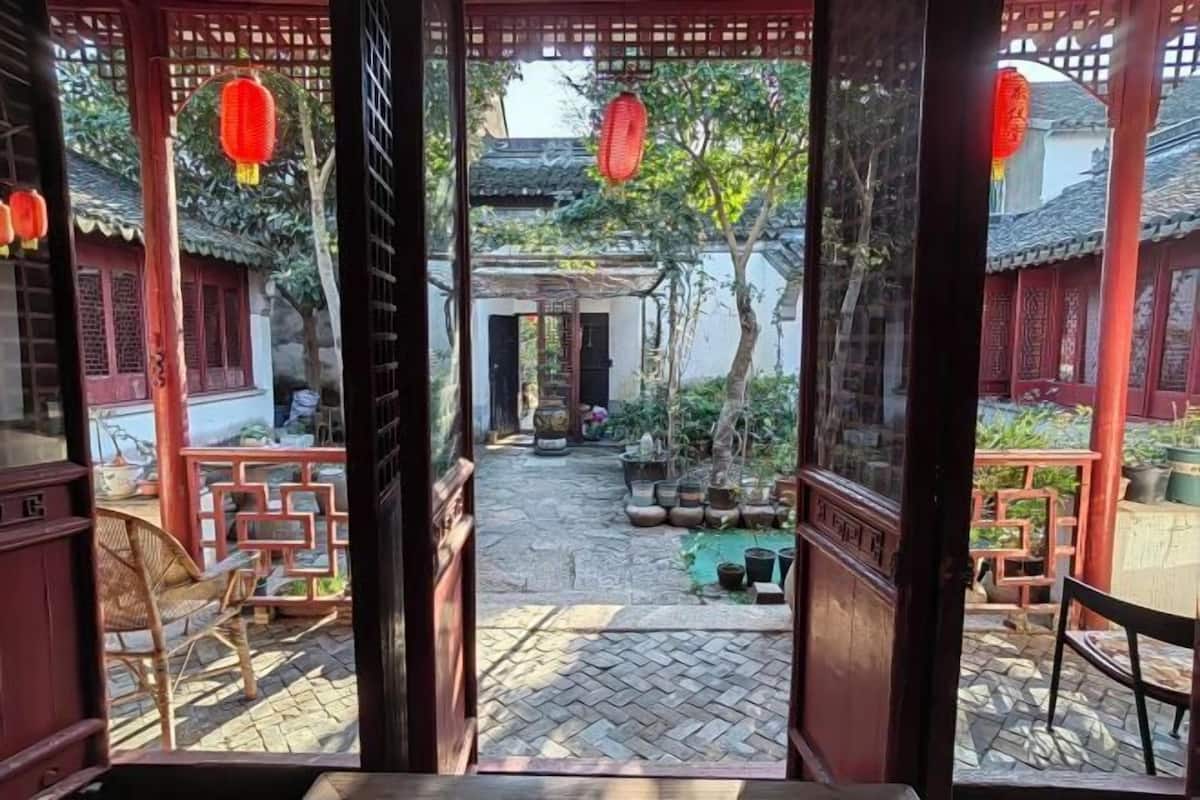 A traditional courtyard with tiled flooring, wooden furniture, and red lanterns.