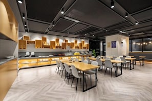 A modern dining area with a long counter, multiple tables, and chairs. - Free Living Hotel (Daishan)