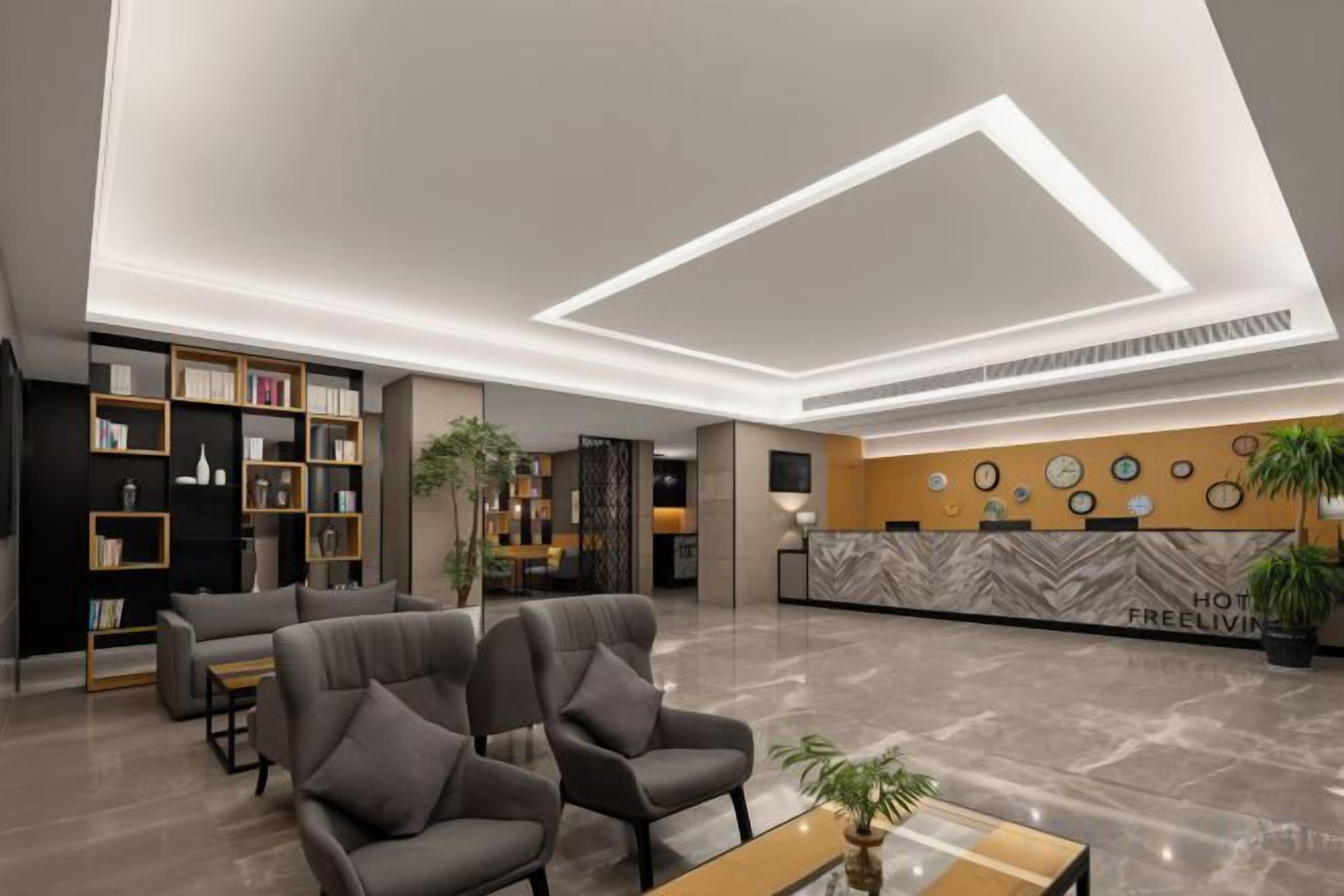 Un vestíbulo de hotel con mostrador de recepción, zona de estar y estanterías.