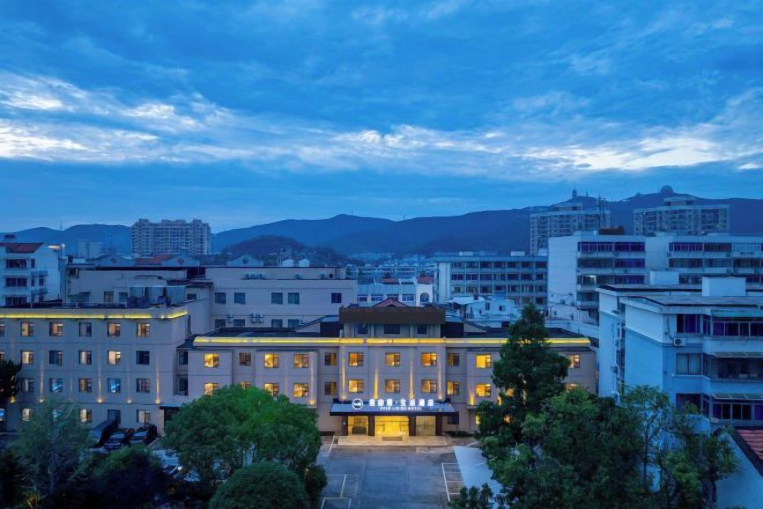 A hotel with a central courtyard, surrounded by buildings, under a twilight sky.