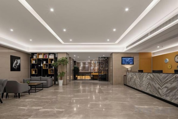 A hotel lobby with a reception desk, seating area, and a large screen. - Free Living Hotel (Daishan)