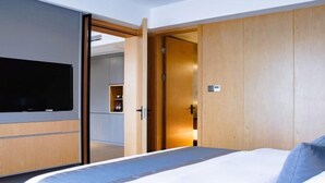 Ein modernes Hotelzimmer mit einem großen Bett, einem Holzschrank und einem an der Wand befestigten Fernseher.