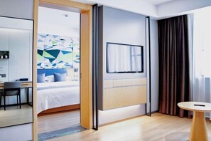 A modern hotel room with a bed, a TV mounted on the wall, a desk, and a chair. - Free Living Hotel (Daishan)
