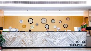 Ein Hotelrezeptionstresen mit einer Marmor-Muster-Theke und mehreren Uhren an der Wand.