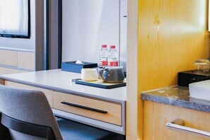 A compact hotel room with a kitchenette, a desk with a chair, a bed, and a window. - Free Living Hotel (Daishan)