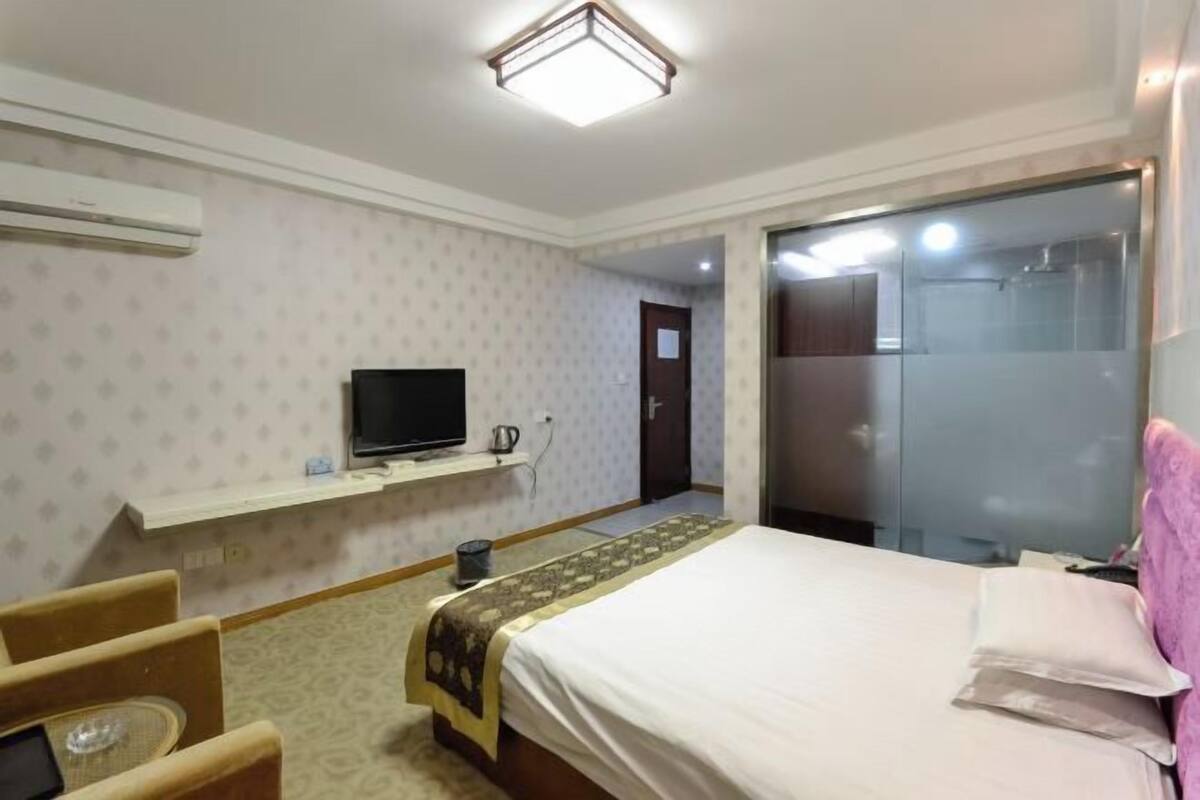 Una habitación de hotel con cama, televisión, una mesita y una silla.