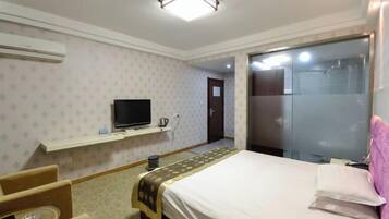 Una habitación de hotel con cama, televisión, una mesita y una silla.